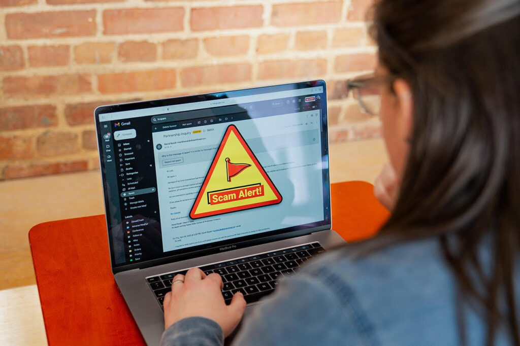 Student working on her laptop. The screen displays a scam alert message.
